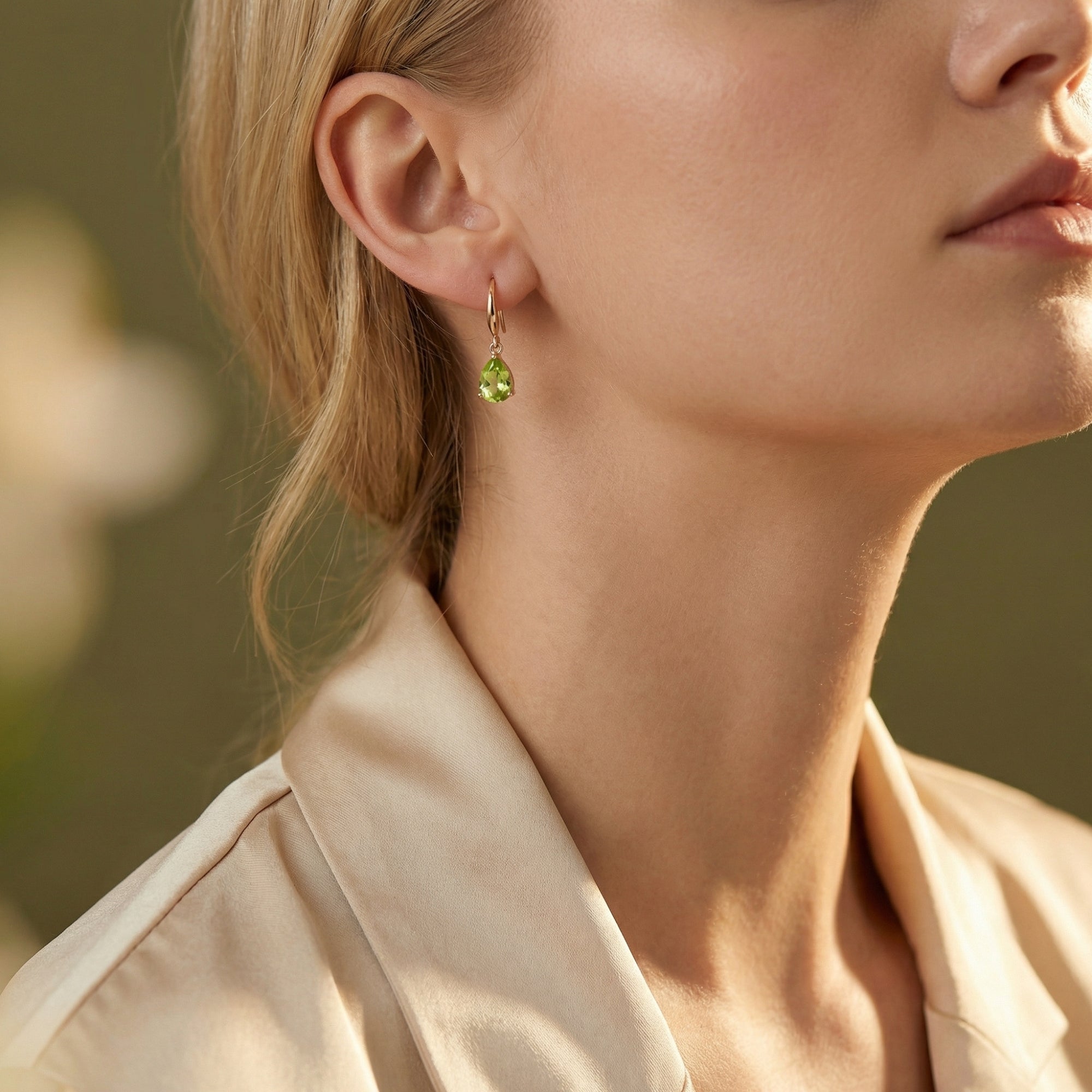 Side profile of a model wearing the Fiorella pear cut peridot drop earrings in 18K rose gold vermeil.