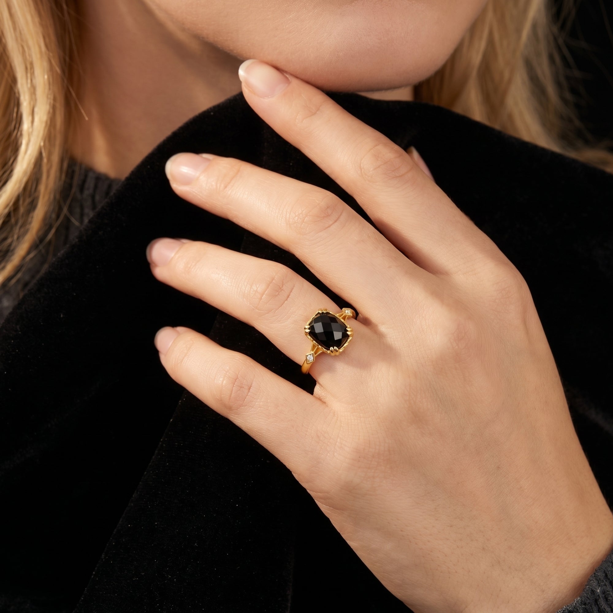 Close-up of the Bellamira natural onyx ring in 18K gold plating worn on a finger against black velvet.