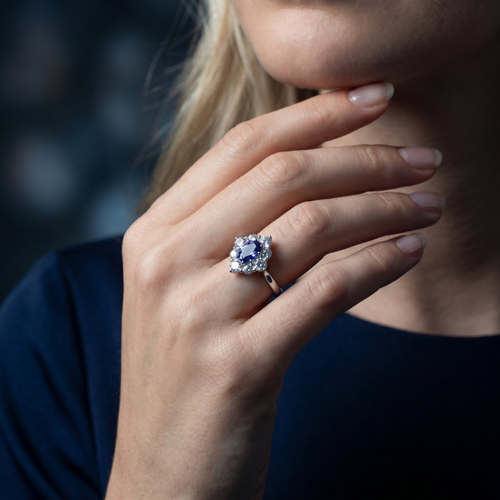 Silver Lirienne ring with an oval tanzanite halo worn on a model's hand, highlighting the floral design.