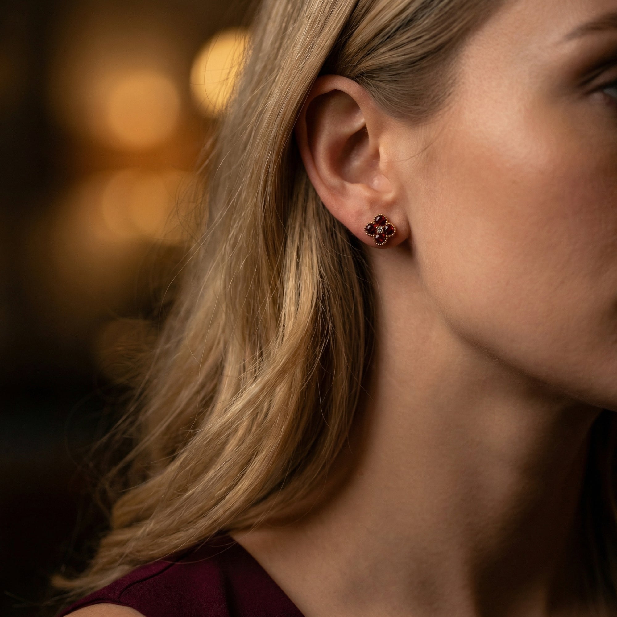 Side view of a model wearing the Ambrosia garnet and diamond floral stud earrings in 18K yellow gold.