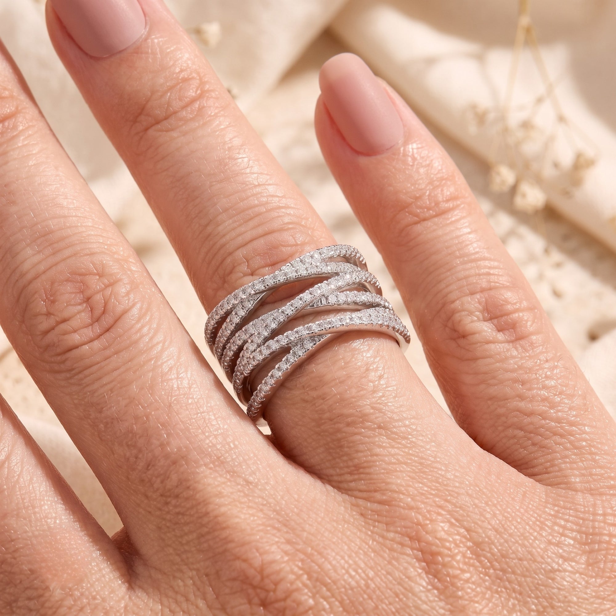 Sterling silver crossover ring with simulated diamonds shown on a model's hand.
