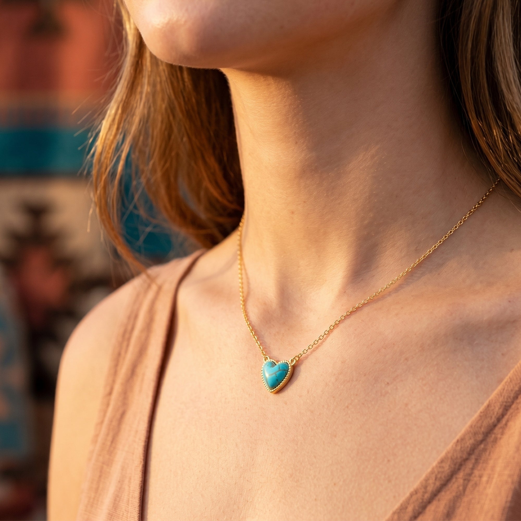 Side view of a model wearing the gold heart turquoise necklace, highlighting the vibrant blue stone and delicate chain.