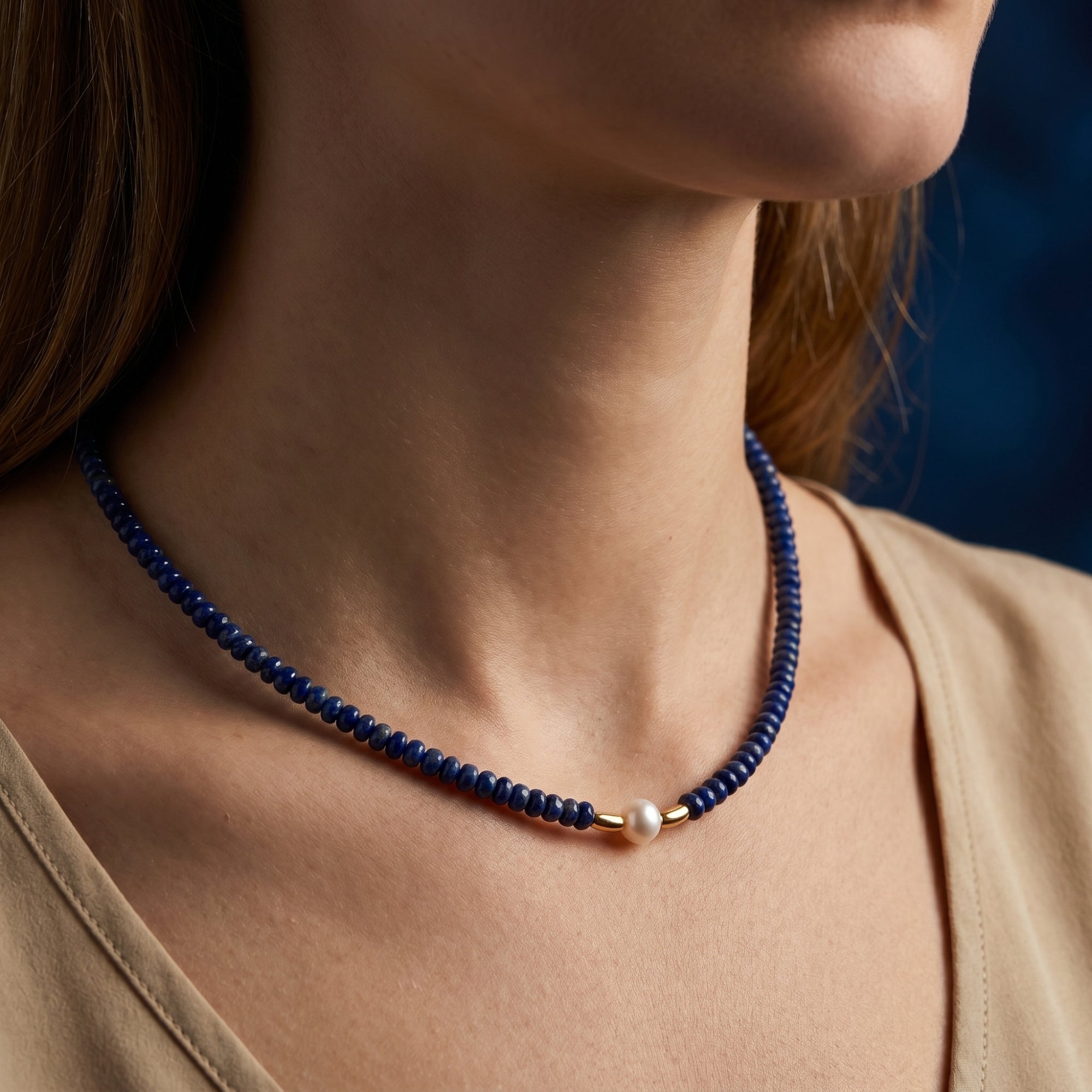 Close-up of a woman wearing a 5mm natural lapis beaded necklace featuring a central white pearl and gold accents.
