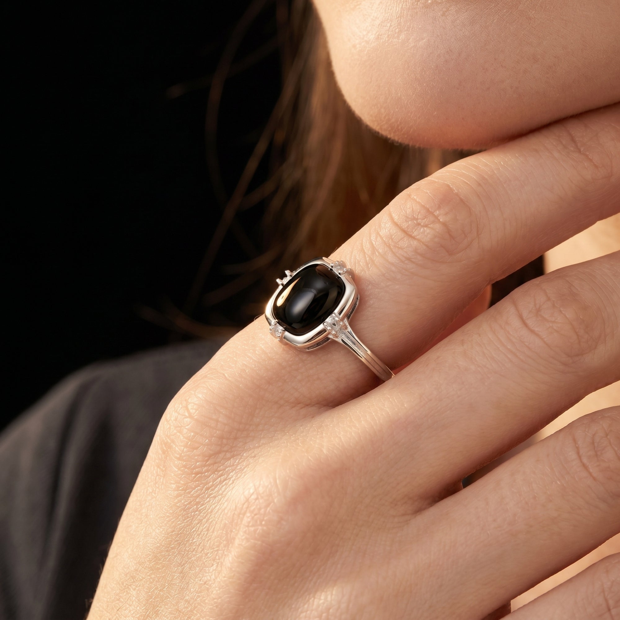 Side view of the cushion cut black onyx sterling silver ring worn on a finger to show scale and design details.