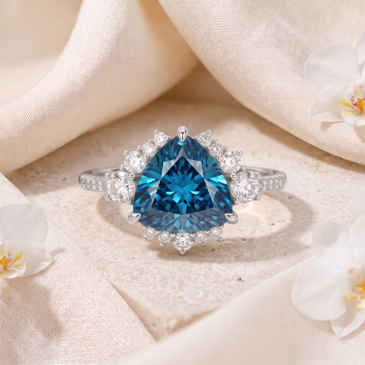 A white gold engagement ring featuring a trillion-cut blue moissanite surrounded by a diamond cluster halo.