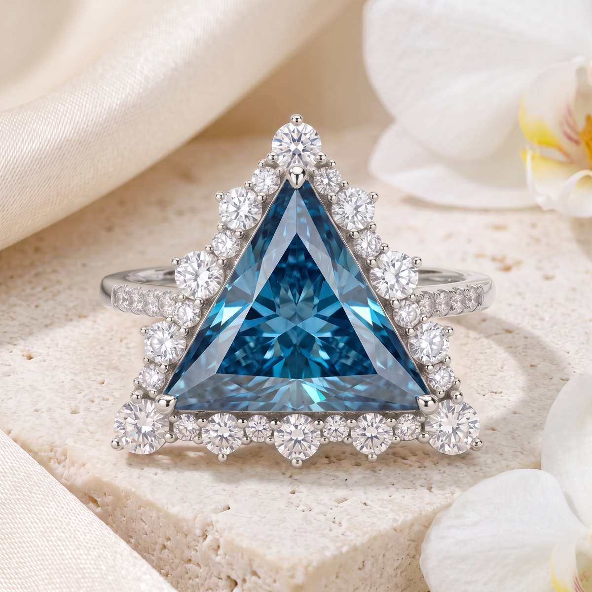 Front view of a trillion cut blue moissanite halo ring in white gold on a stone block.