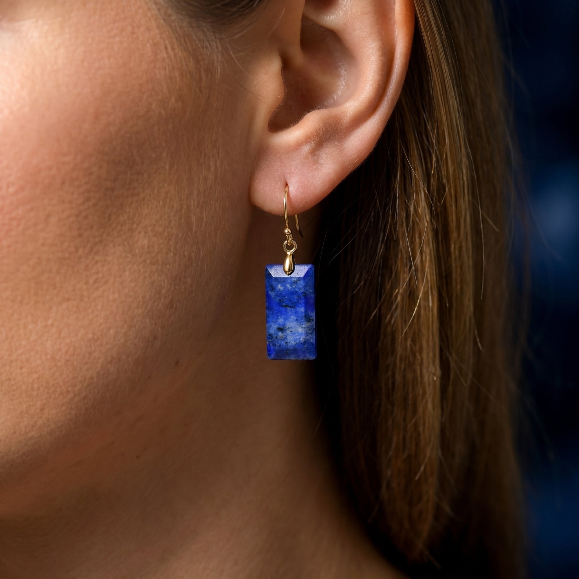 Side view of a model wearing a gold-plated rectangular natural lapis lazuli pillar earring.