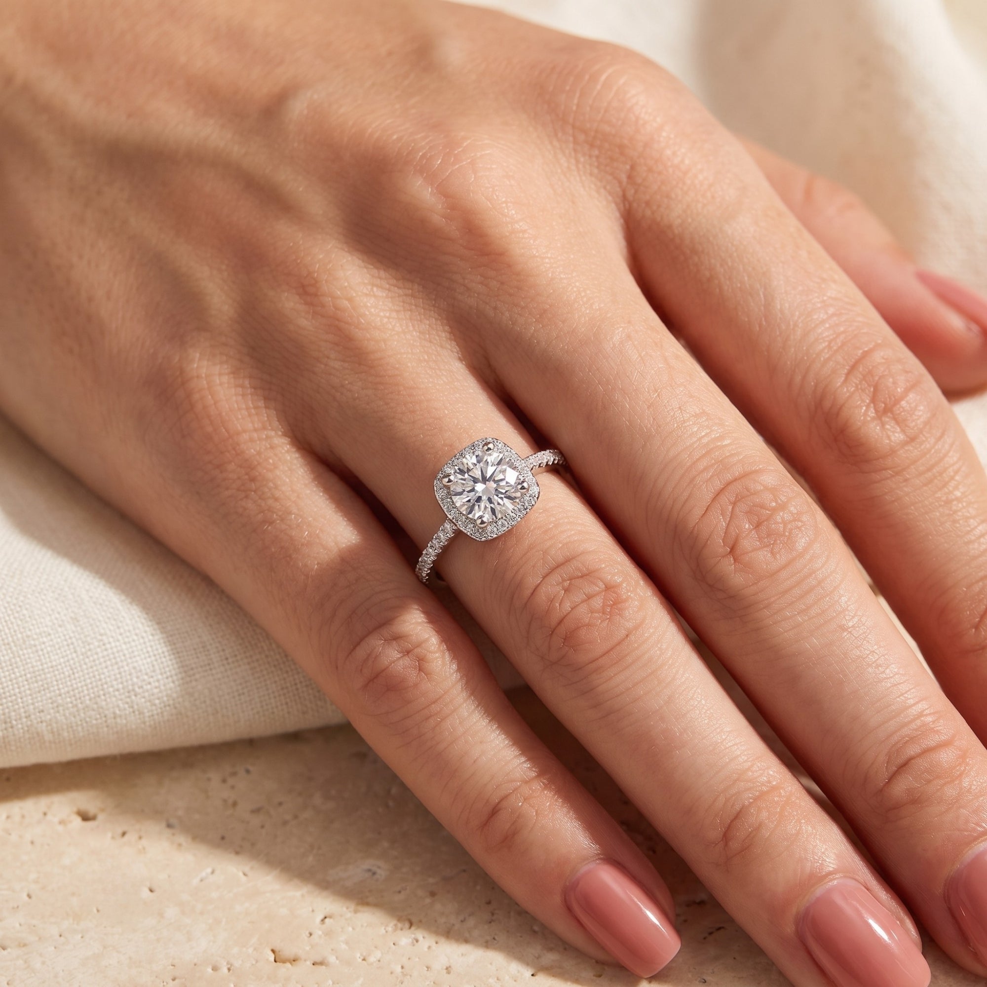 Top view of the Celeste cushion halo ring in sterling silver on a model's finger.