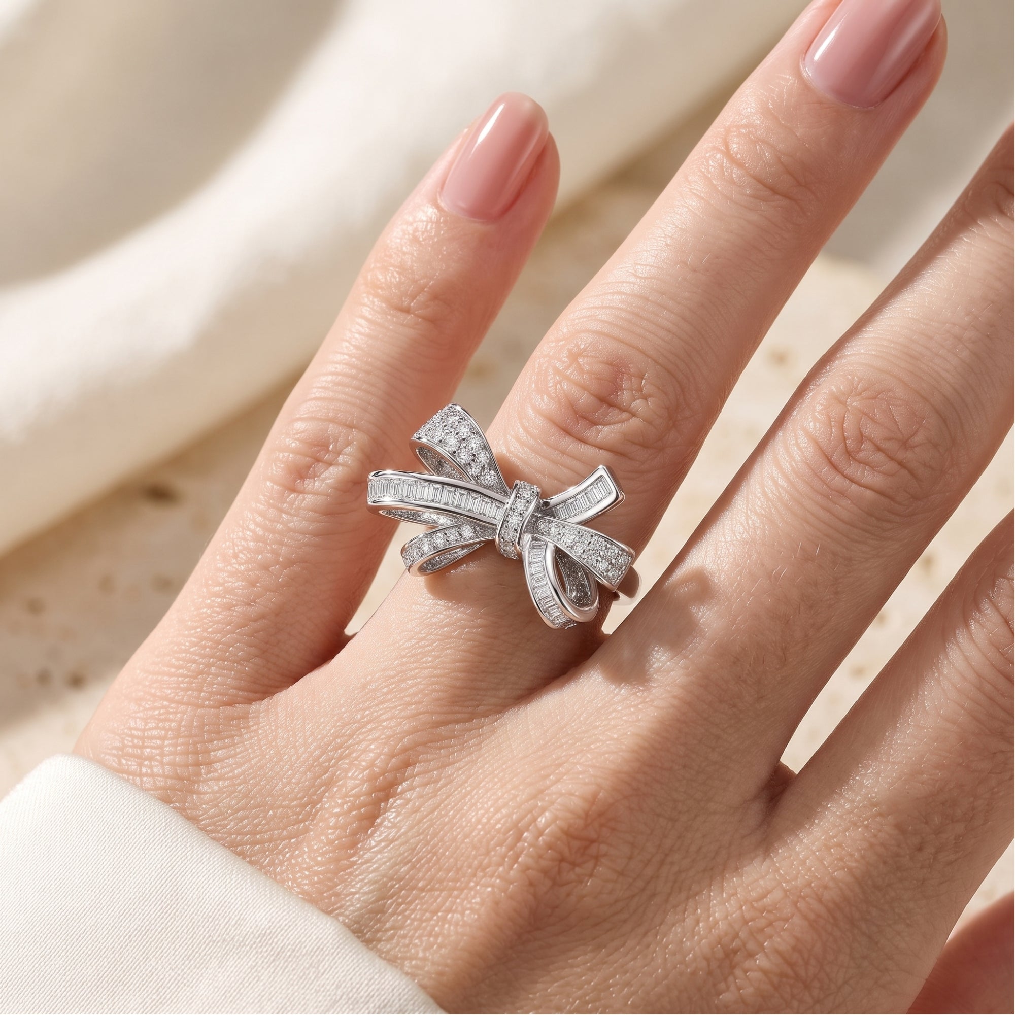 Sterling silver bow ring with pavé diamonds shown on a finger for scale.
