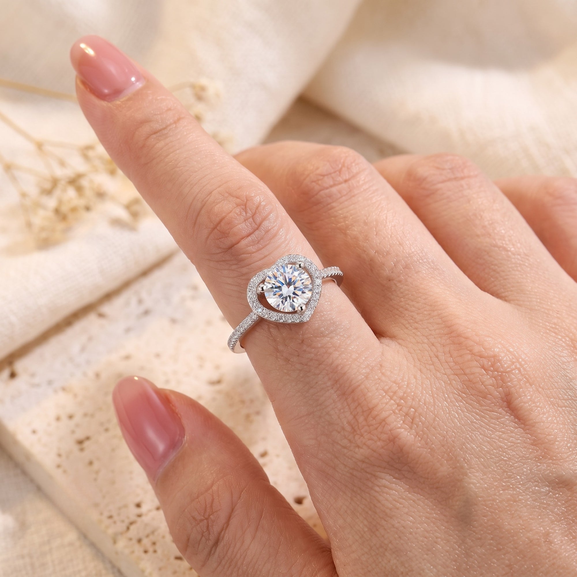 Top-down view of the silver heart halo ring on a finger showing scale and sparkle.