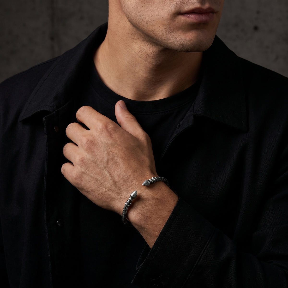 Model wearing the open silver finial cuff bracelet with his hand across a black jacket.