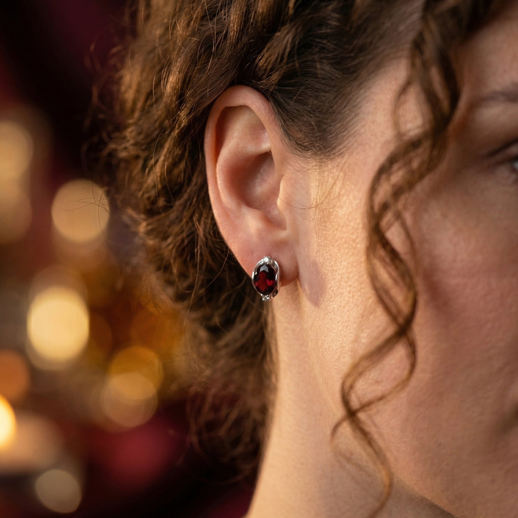 Side profile of a model wearing the Alessia 8x10mm oval garnet drop earrings in sterling silver.