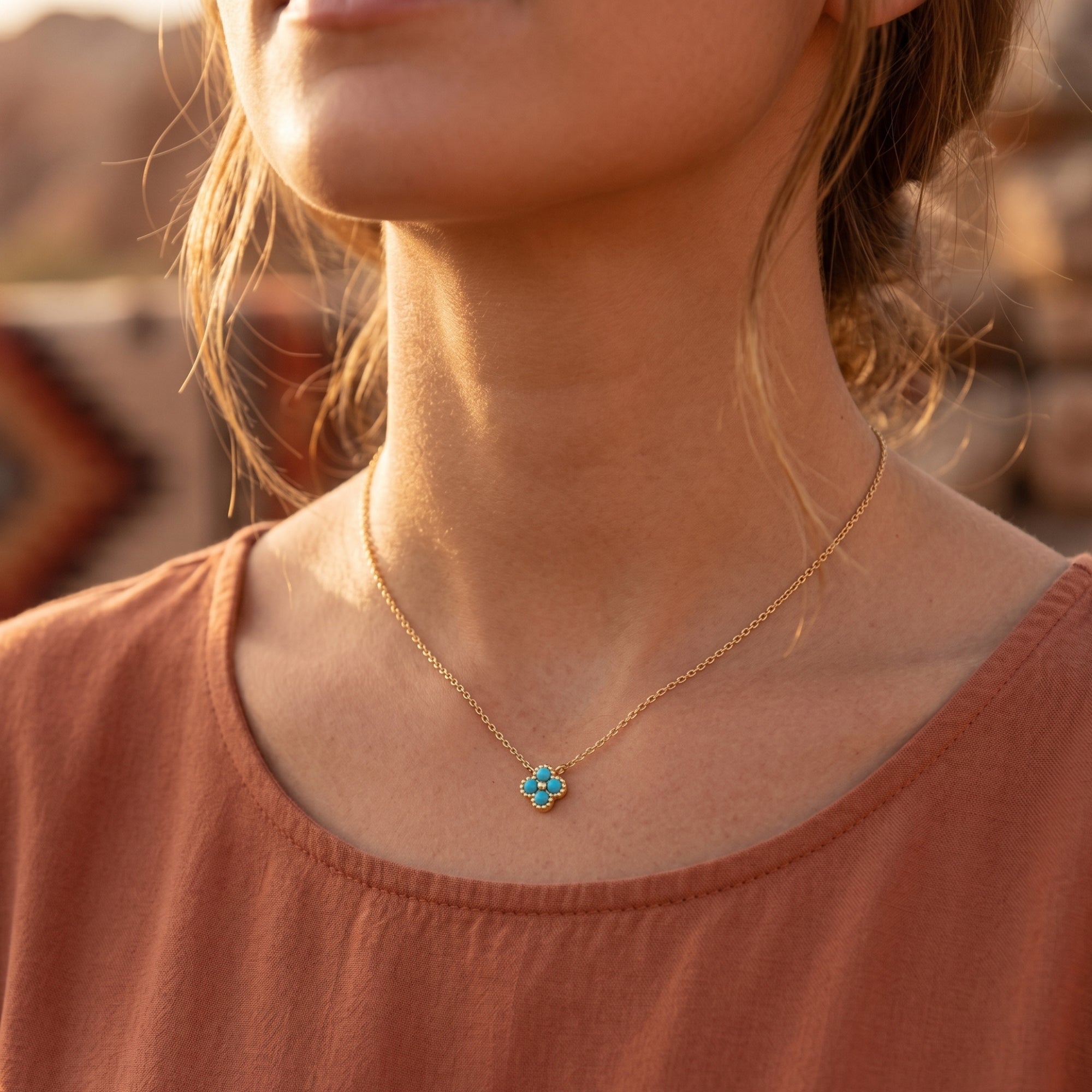 Front view of a woman wearing the gold flower-shaped turquoise necklace in a desert setting.
