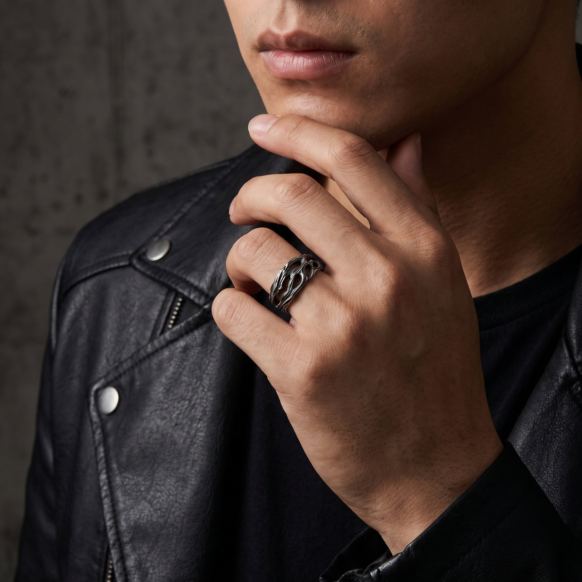 Model wearing the textured openwork silver ring with a black shirt and leather jacket visible.