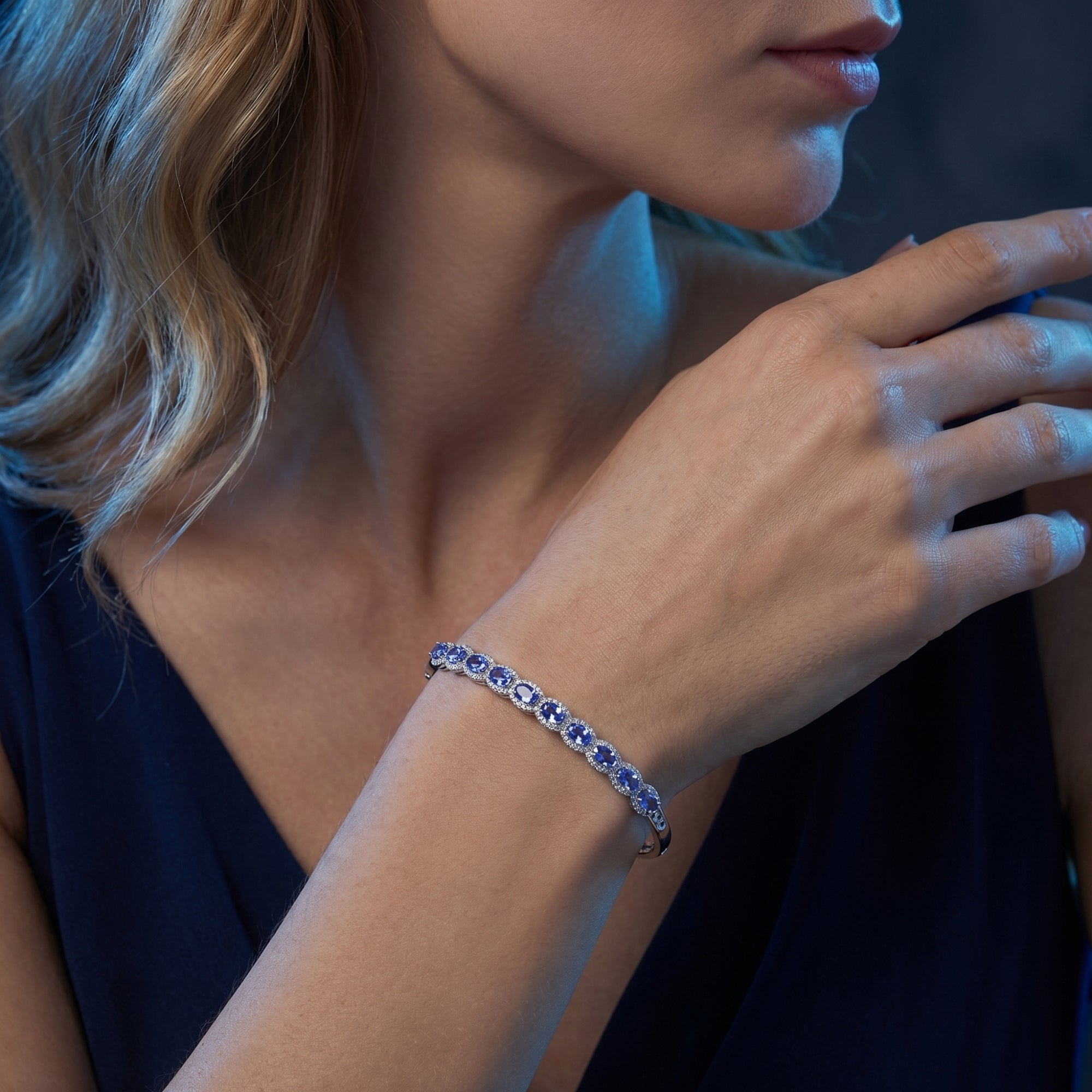 White gold line bracelet with eleven oval natural tanzanite stones shown on a model's wrist.