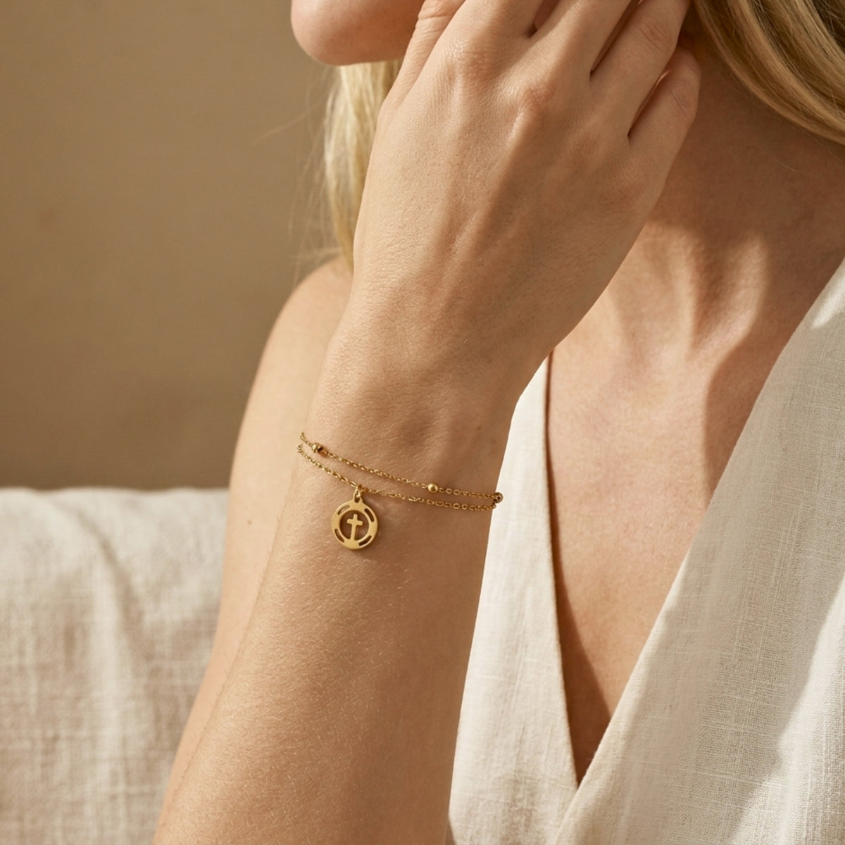 Lifestyle view of a woman wearing the double-strand cross bracelet with a white linen top.