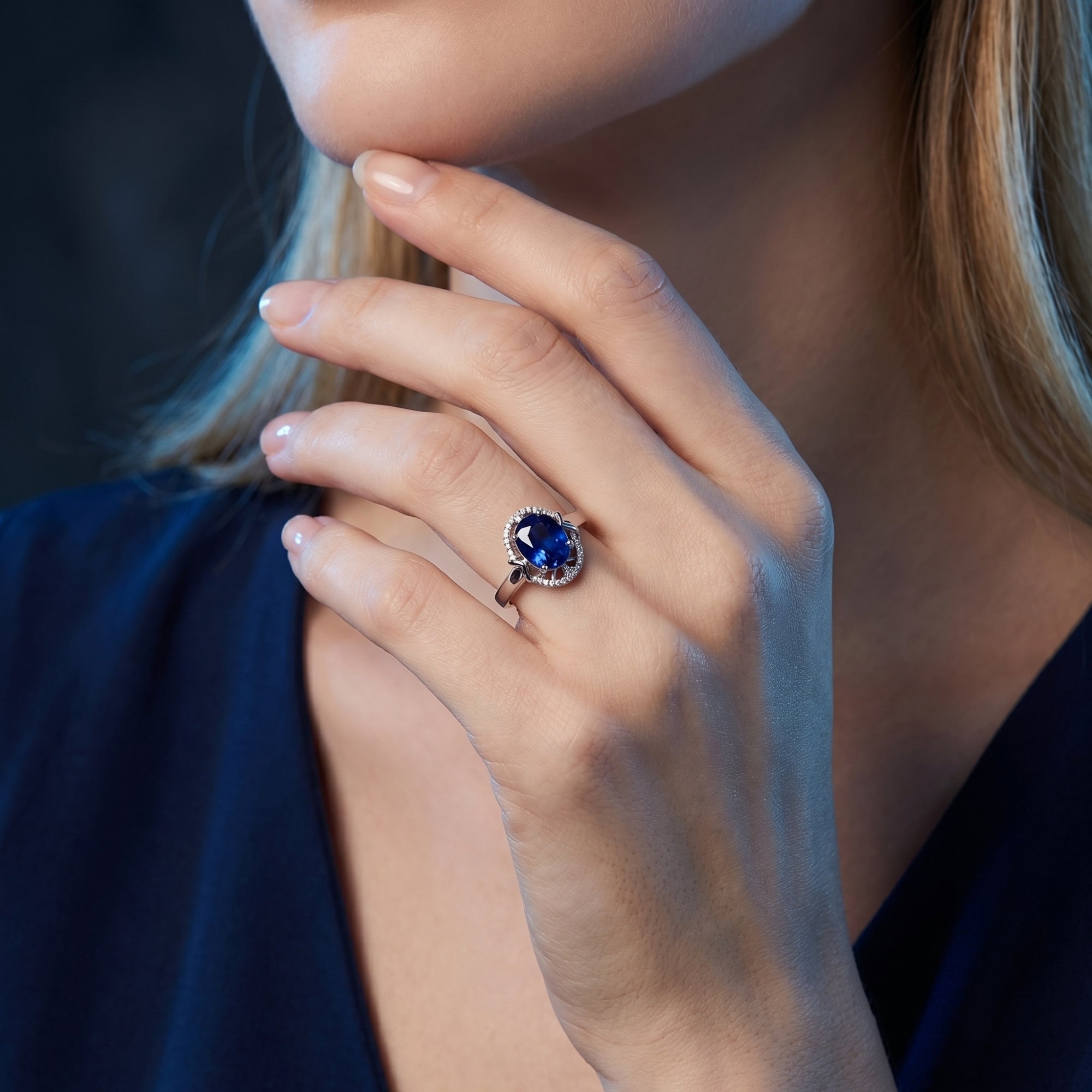 A woman wearing the 18K white gold oval tanzanite ring with a diamond halo, showing its scale on the hand.