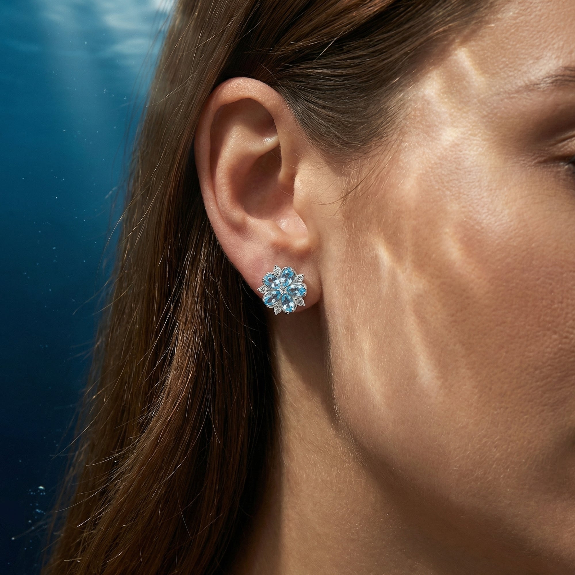 Close-up of a marquise aquamarine flower earring in sterling silver worn on a model's ear.