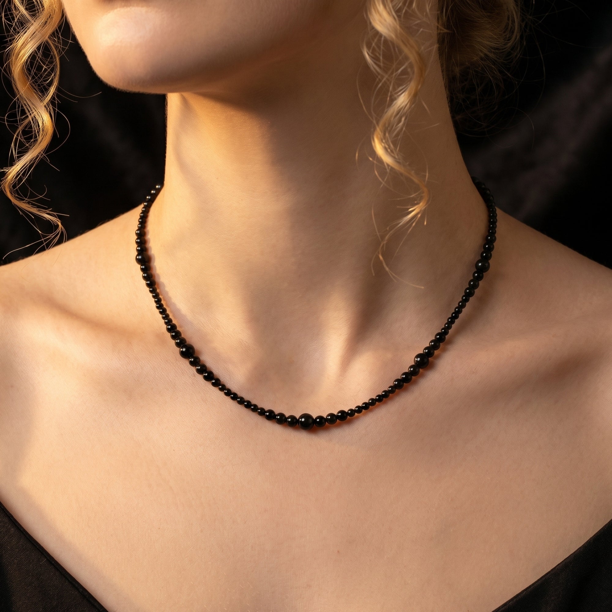 Front view of a model wearing the Ebon Flow natural black onyx graduated bead necklace.