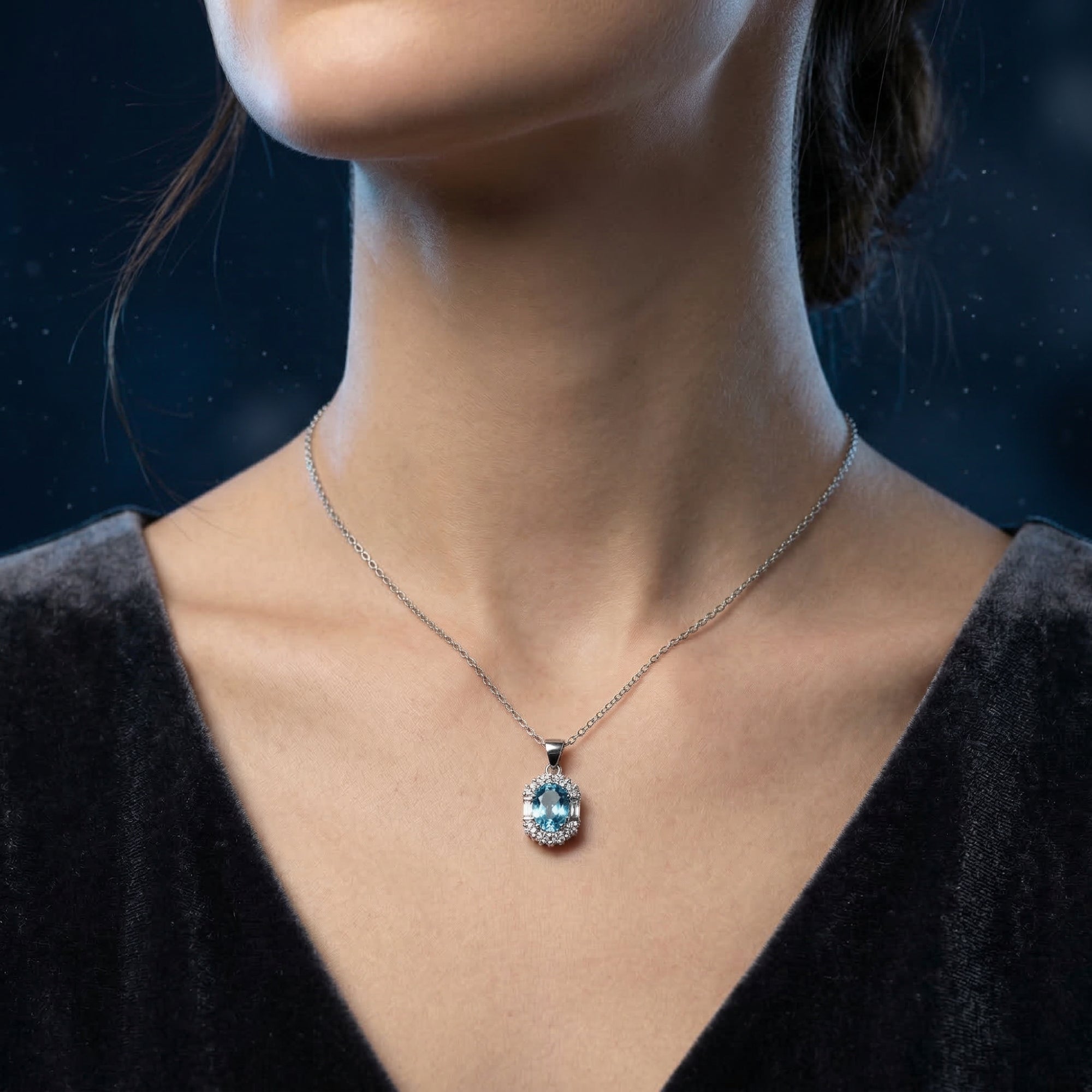 Model wearing the oval blue topaz pendant necklace in white gold paired with a dark velvet dress.