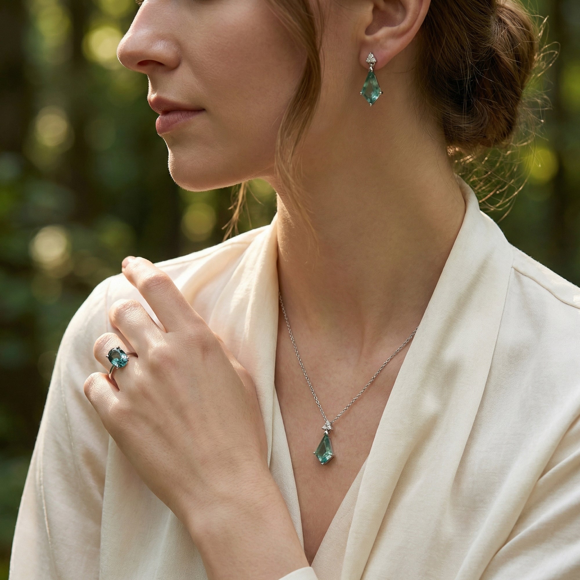 Side view of a model wearing a silver green moissanite ring and geometric moss agate necklace and earrings.