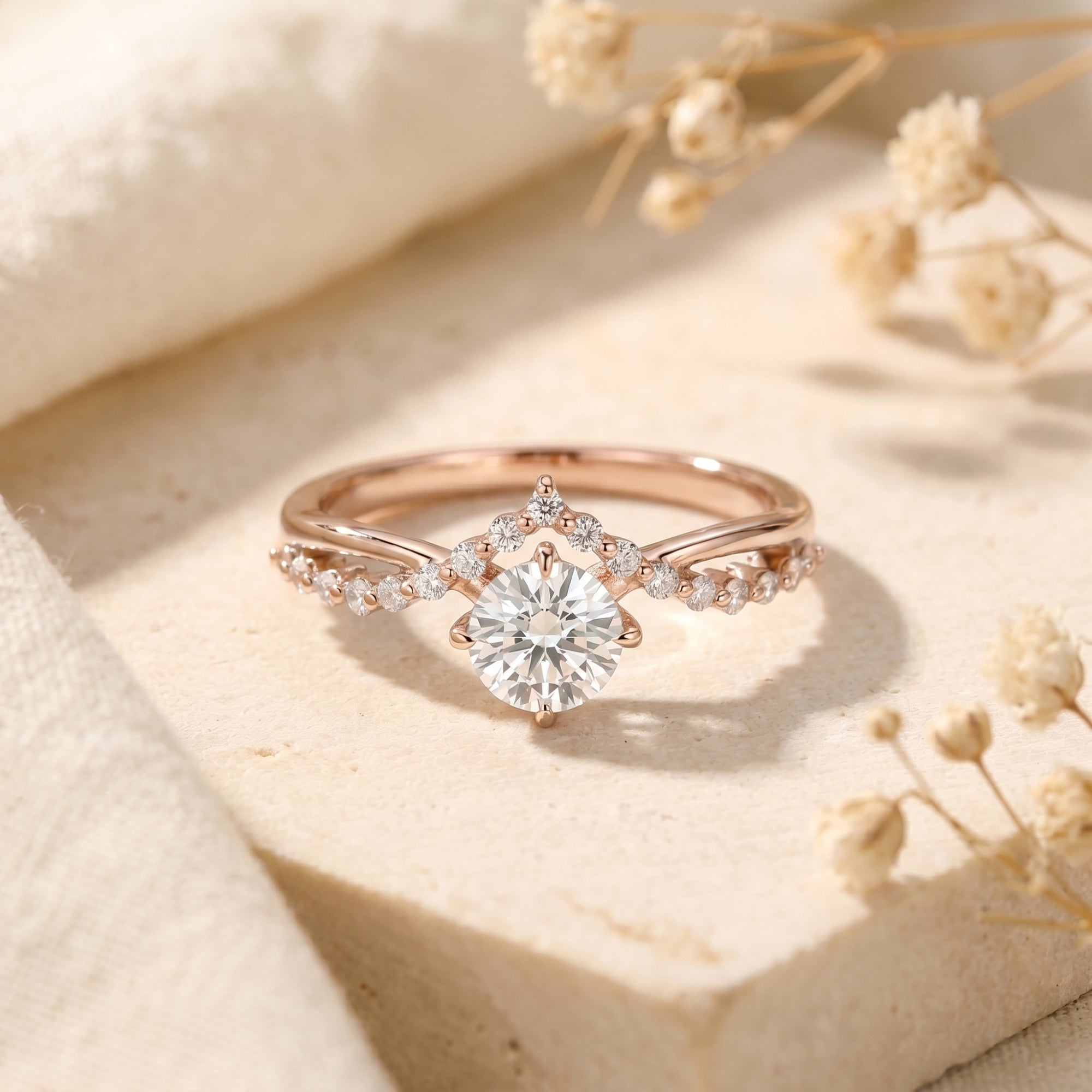 Rose gold Caladienne moissanite ring with a round-cut center stone and crown accent on a textured stone block.