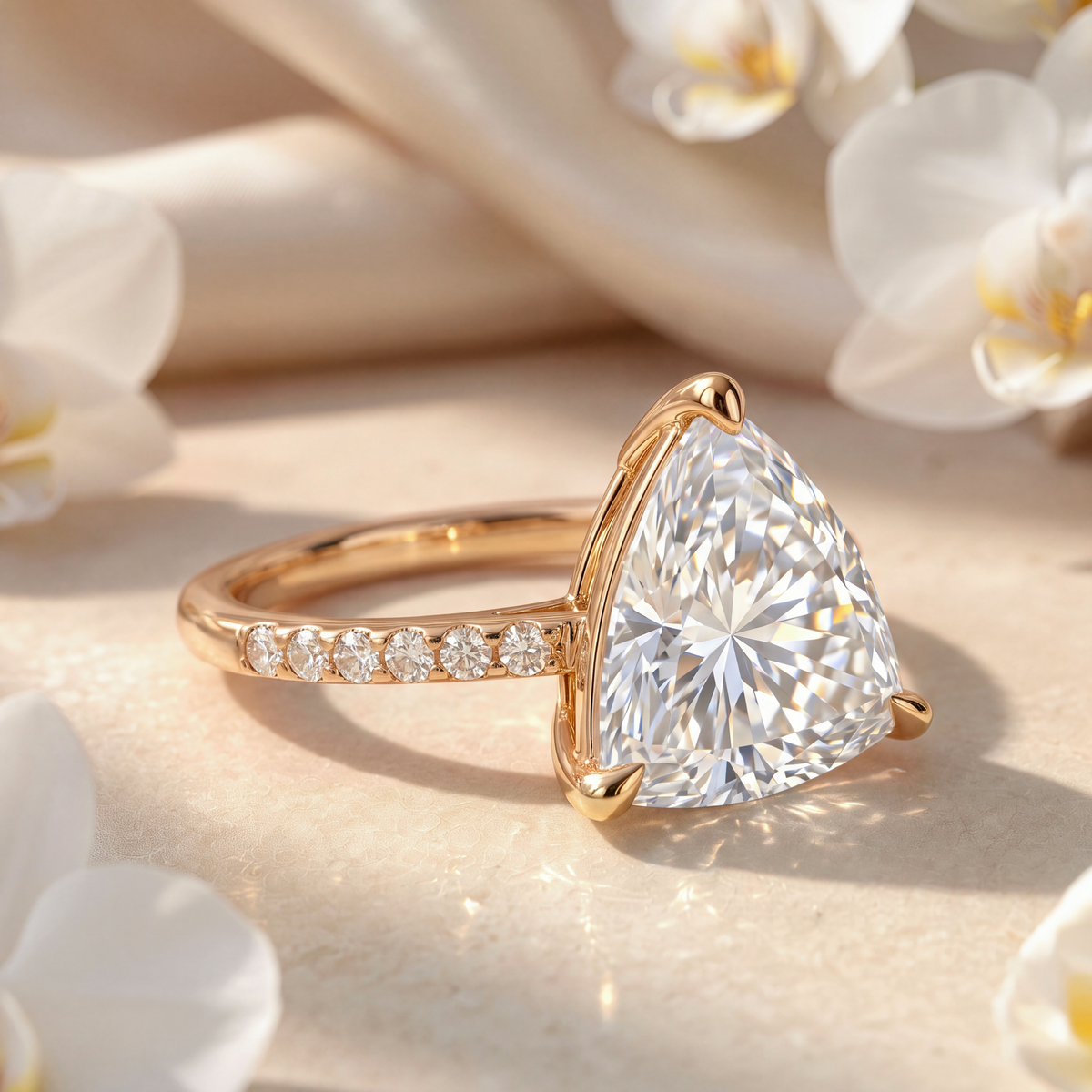 Side view product shot of a yellow gold trillion-cut moissanite engagement ring showcasing its setting and pavé band.