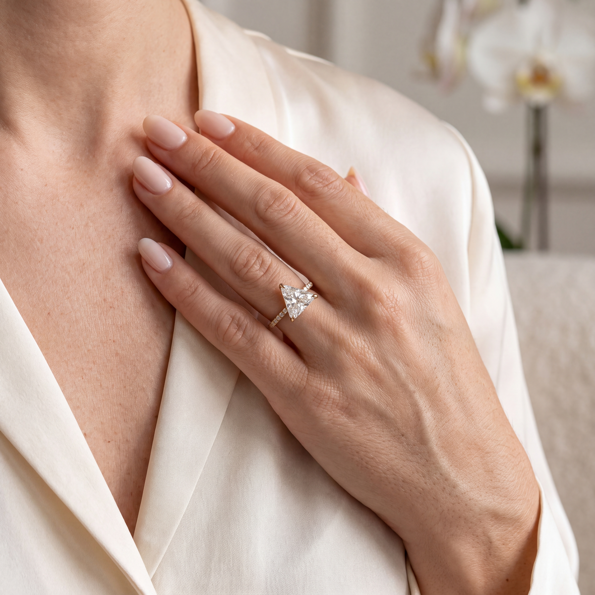 Yellow gold trillion cut moissanite ring styled on a model's hand.