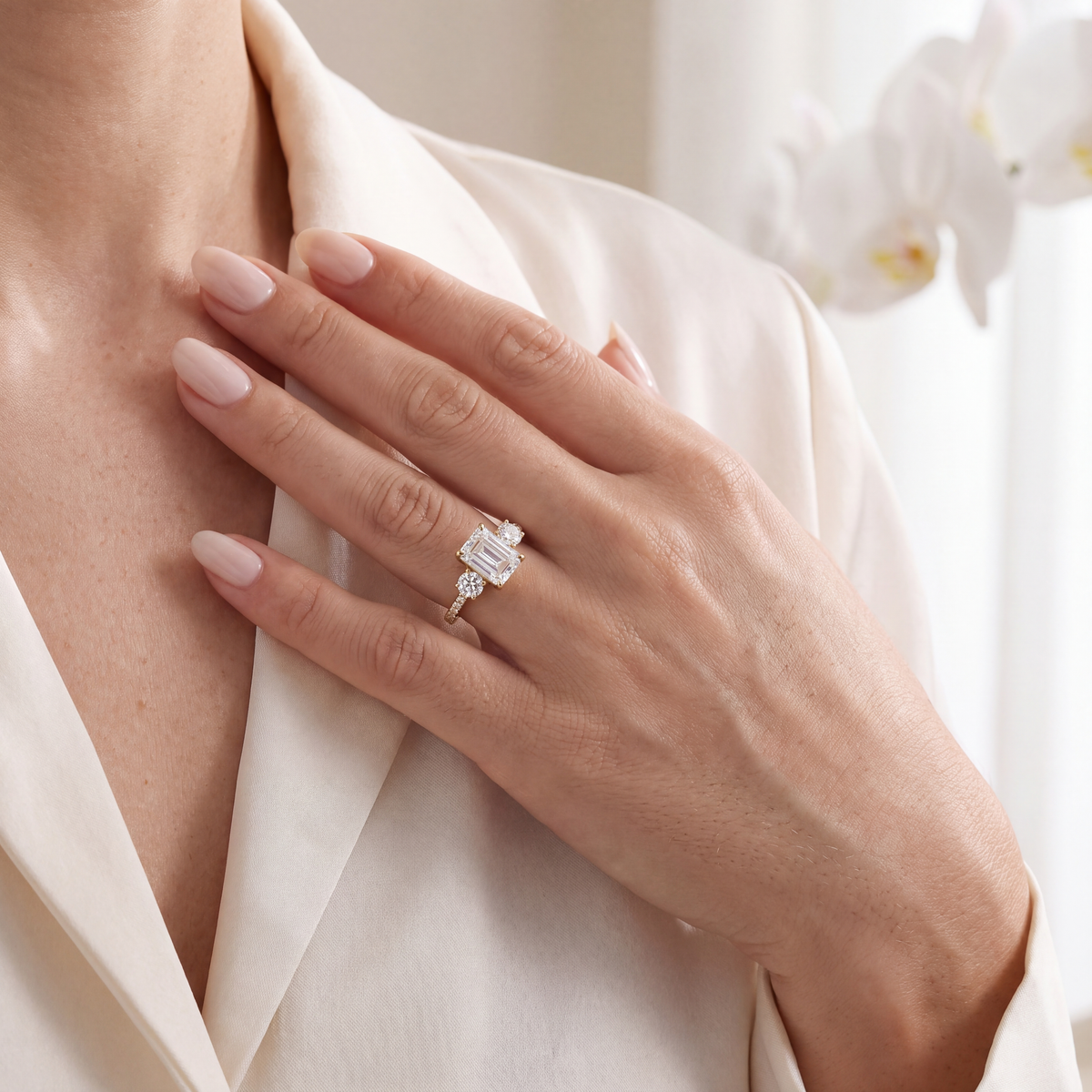 Lifestyle shot of a model wearing a yellow gold emerald cut three-stone moissanite ring.