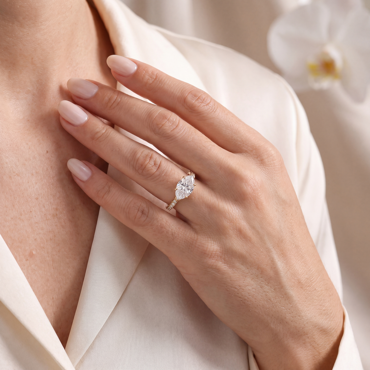 Model wearing a yellow gold east-west marquise moissanite engagement ring with a pavé band.
