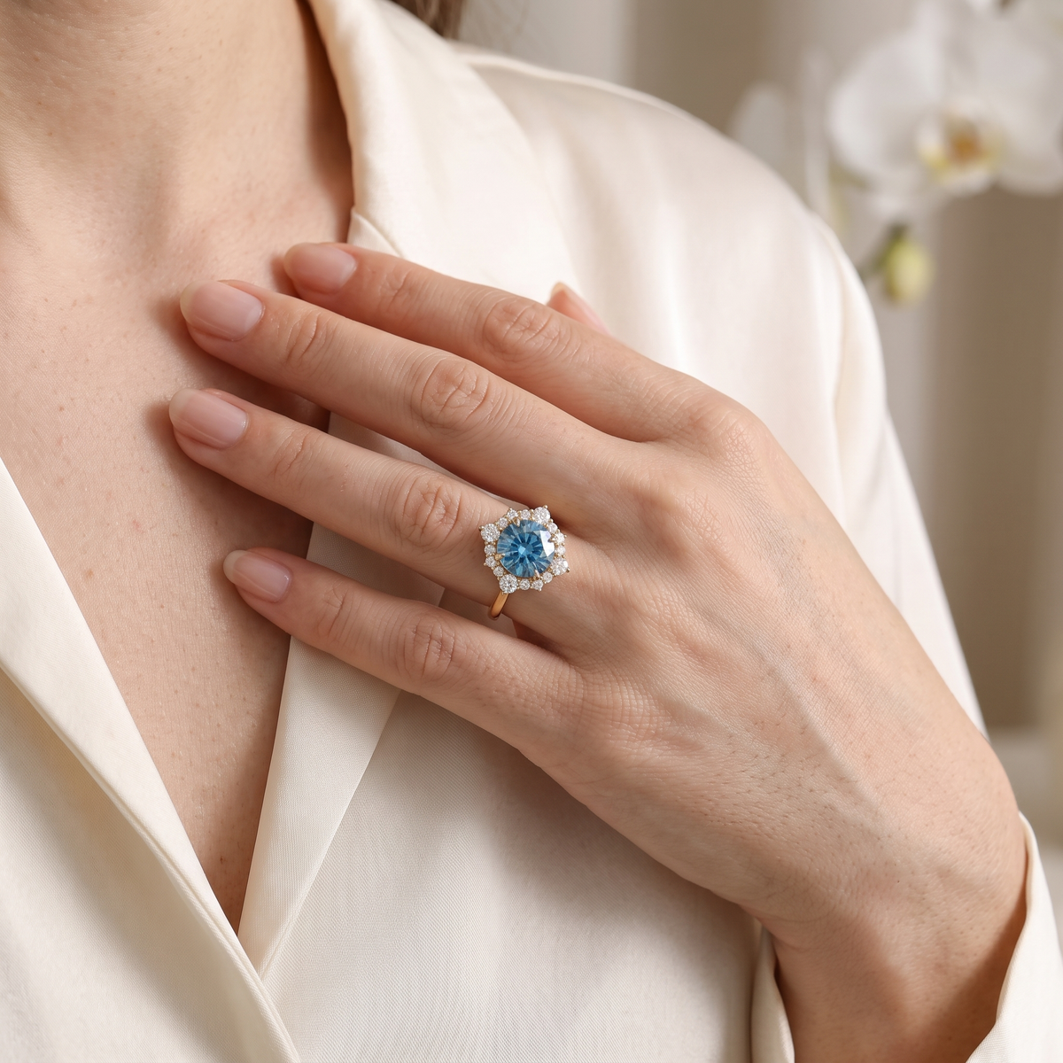 Close-up of a woman wearing a round blue moissanite halo engagement ring in rose gold.