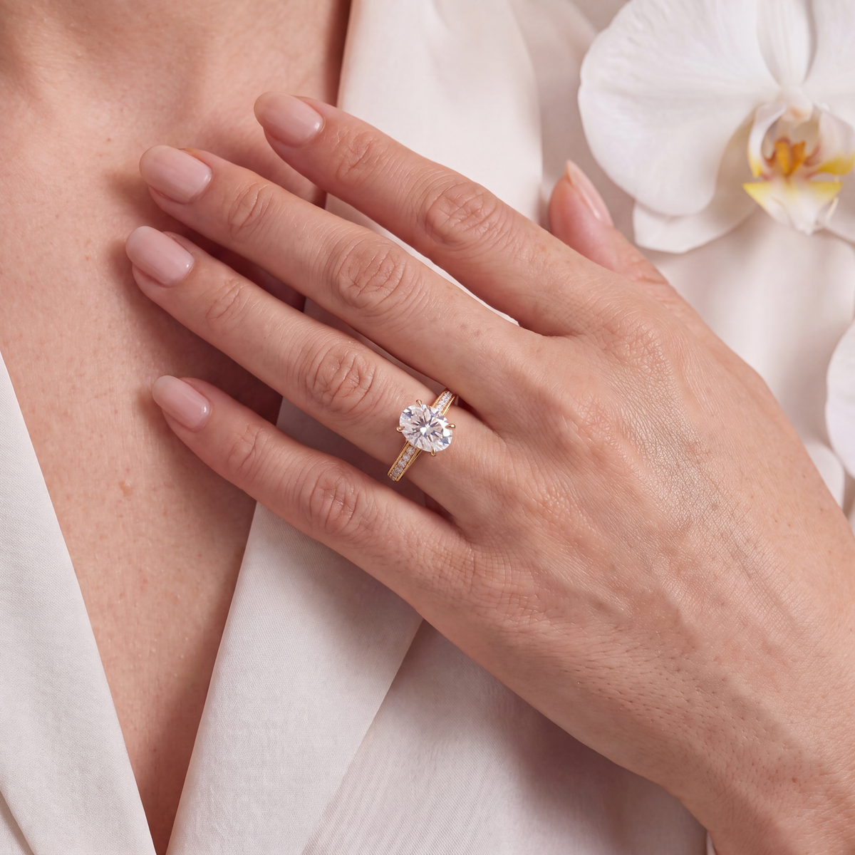 Close-up of a model wearing a yellow gold oval moissanite engagement ring.