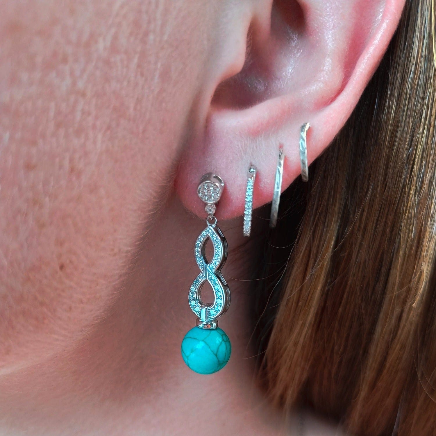 Azure Oceanic Earrings featuring turquoise stones in a sterling silver setting on a models ear natural look