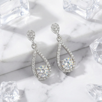 Teardrop sterling silver drop earrings with round zirconia stones on a marble surface with ice cubes.