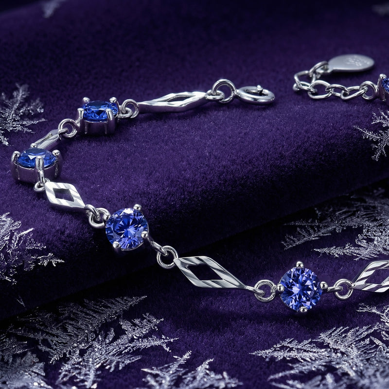 Macro view of a sterling silver station bracelet with round-cut blue-violet simulated tanzanite stones.