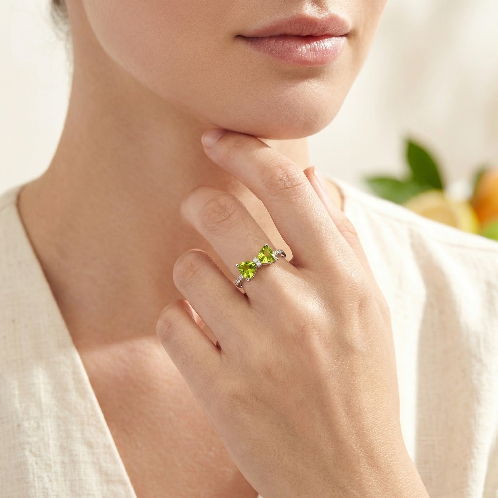 Woman wearing the sterling silver bow ring with vibrant green trillion-cut simulated peridots on her finger.