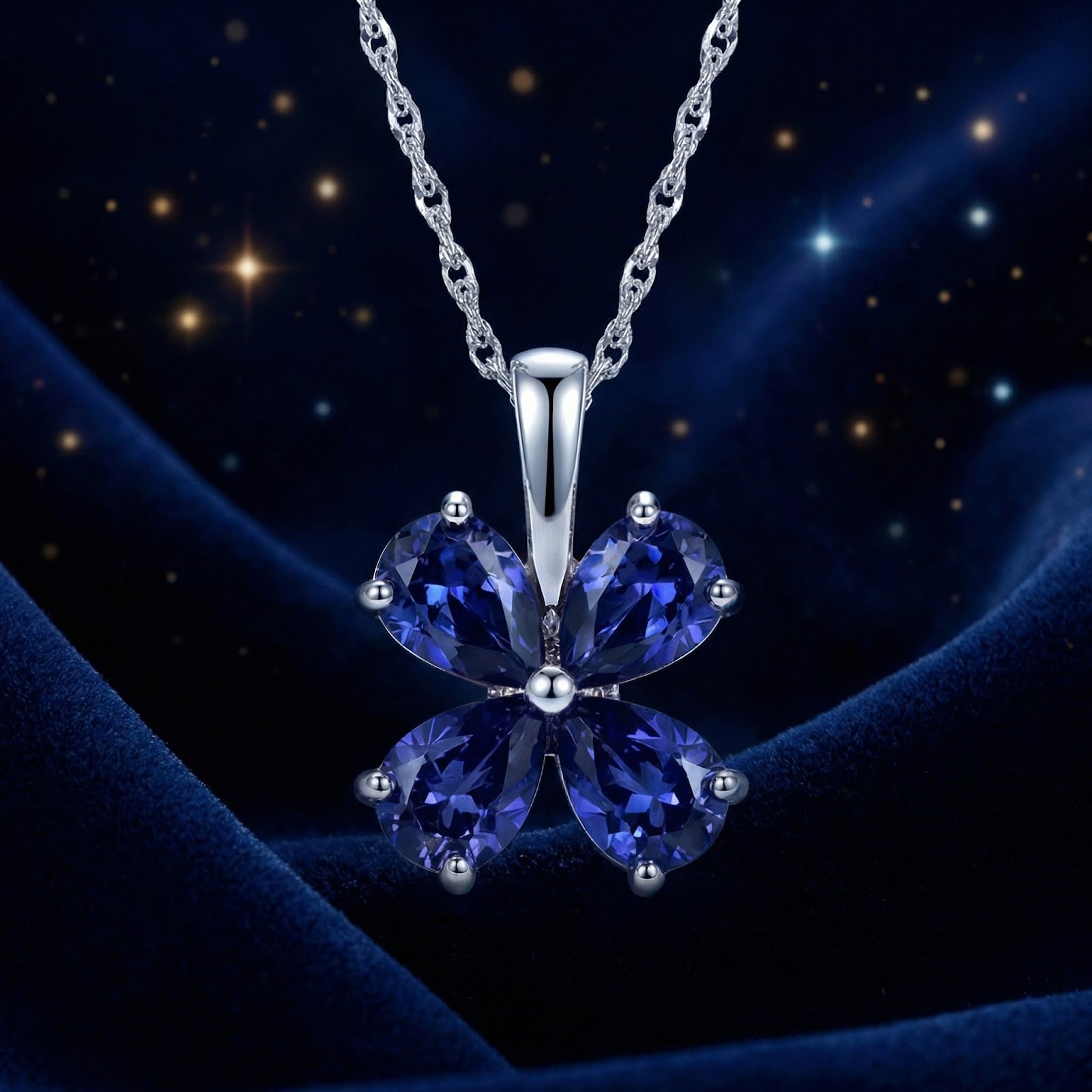 Sterling silver clover necklace with four heart-cut simulated sapphires on a starry blue velvet background.