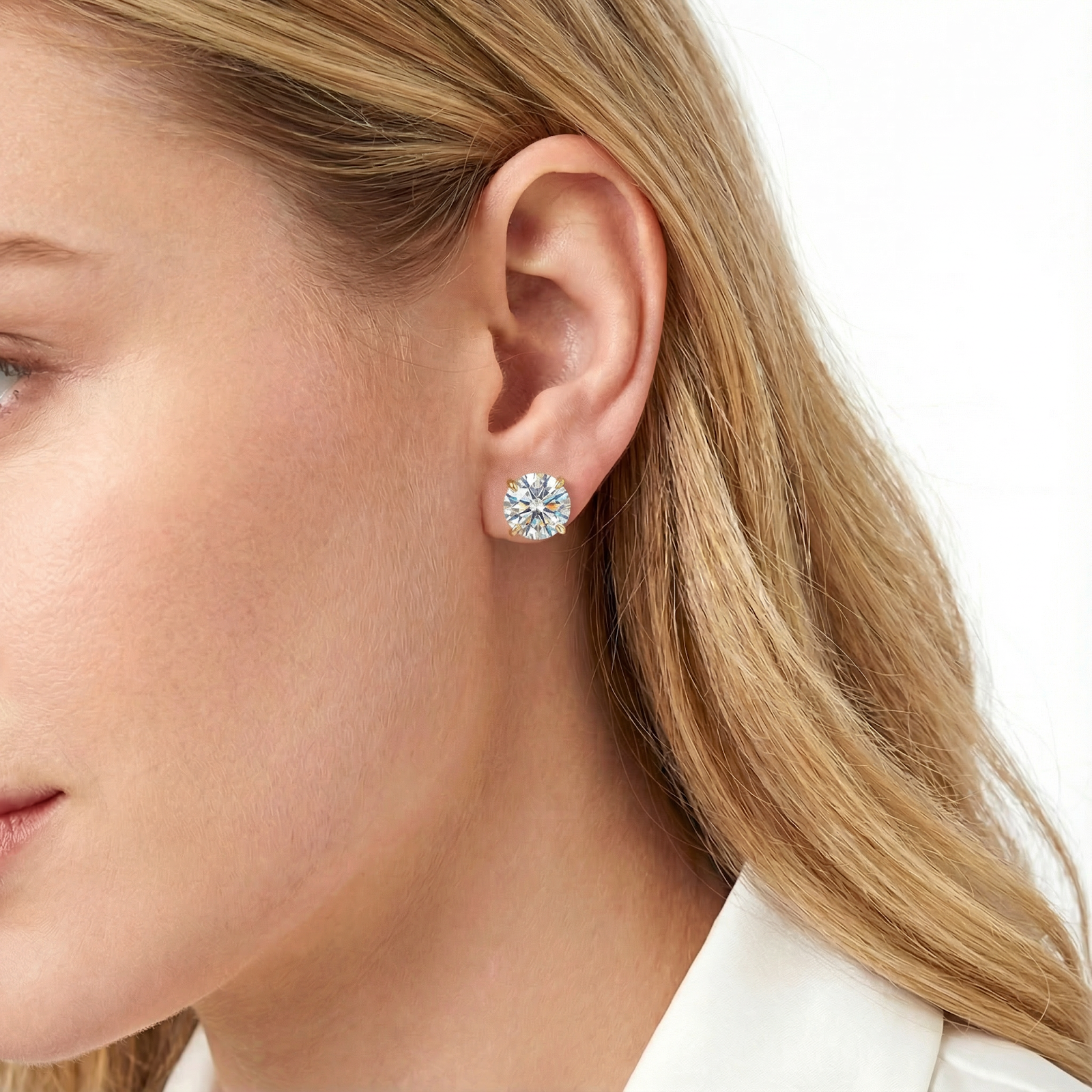 Side view of a woman wearing a gold stud earring with a brilliant round simulated diamond.