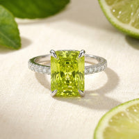 Radiant-cut simulated peridot ring in S925 sterling silver with pavé band, styled with fresh lime slices.