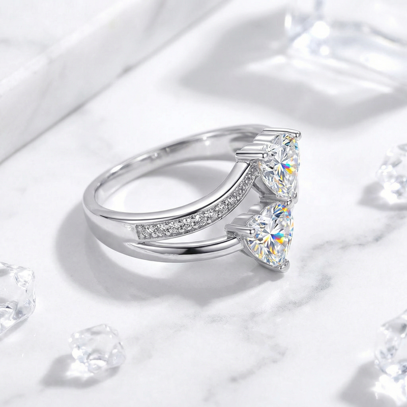 Side view of the Amantina S925 sterling silver bypass ring featuring two heart-cut zirconia stones on marble.