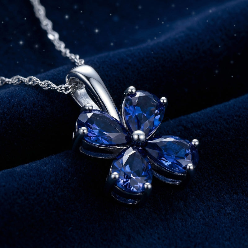 Angled macro view of a sterling silver pendant with four heart-cut simulated sapphires in a clover setting.