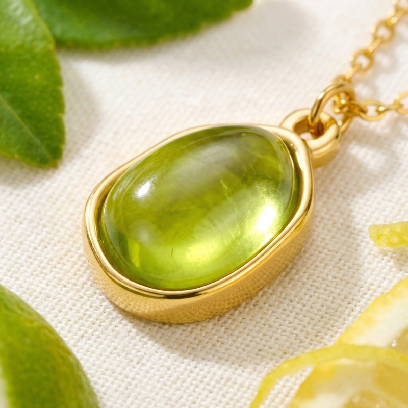 Close-up of a gold-finished stainless steel bezel setting holding a smooth teardrop-shaped green simulated peridot.