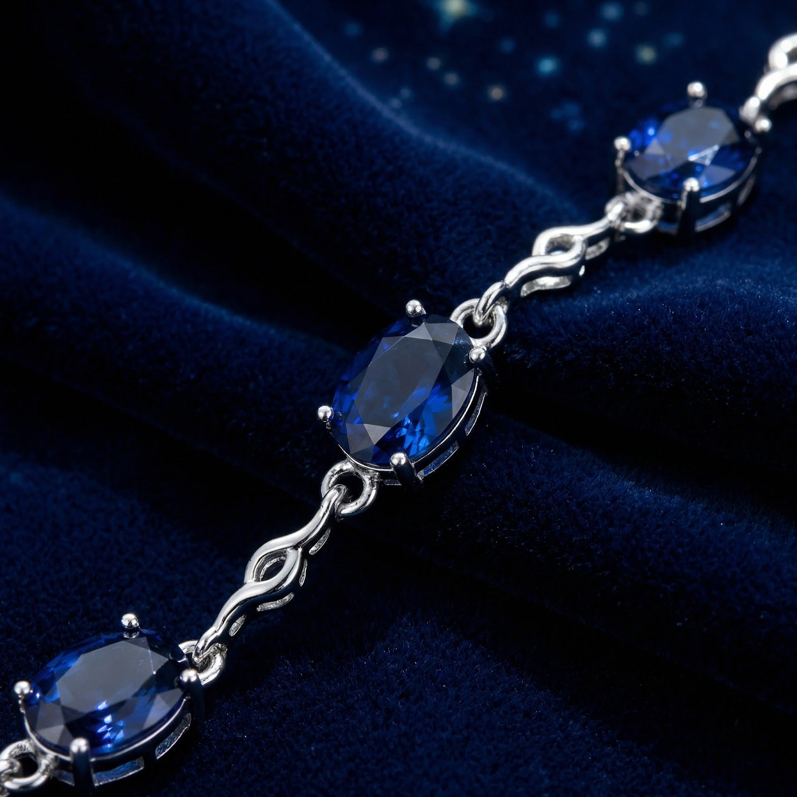 Macro detail of oval-cut simulated sapphires and wavy sterling silver links on the Thalissine station bracelet.