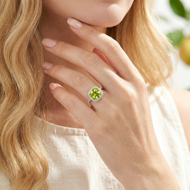 Woman wearing the S925 sterling silver Aevis ring with a cushion cut simulated peridot on her hand.