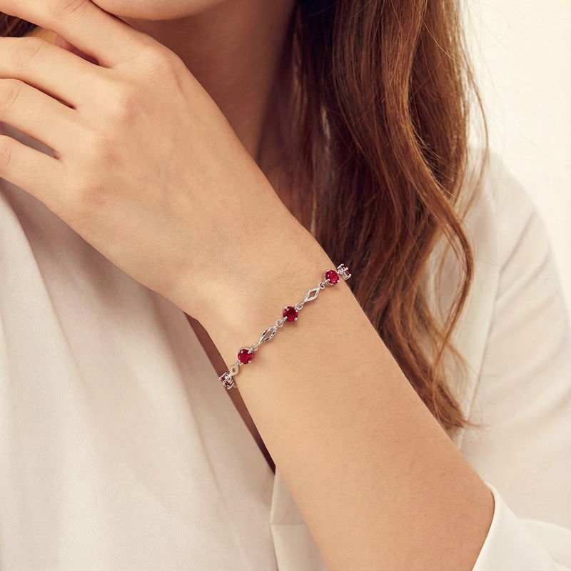 Model wearing the July birthstone station bracelet in sterling silver with pigeon blood red simulated rubies.