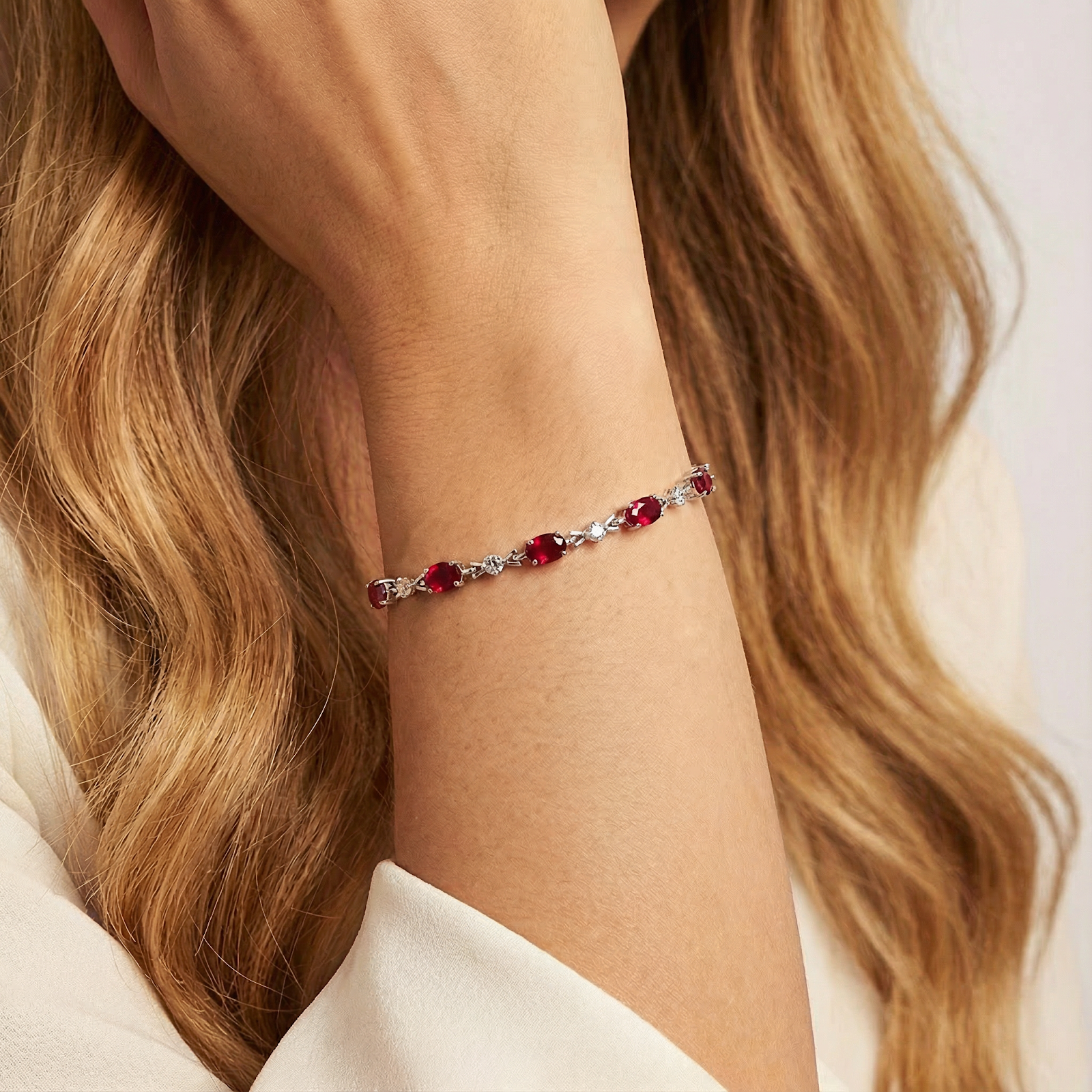 Woman wearing the Vivara oval simulated ruby and sterling silver tennis bracelet on her wrist.