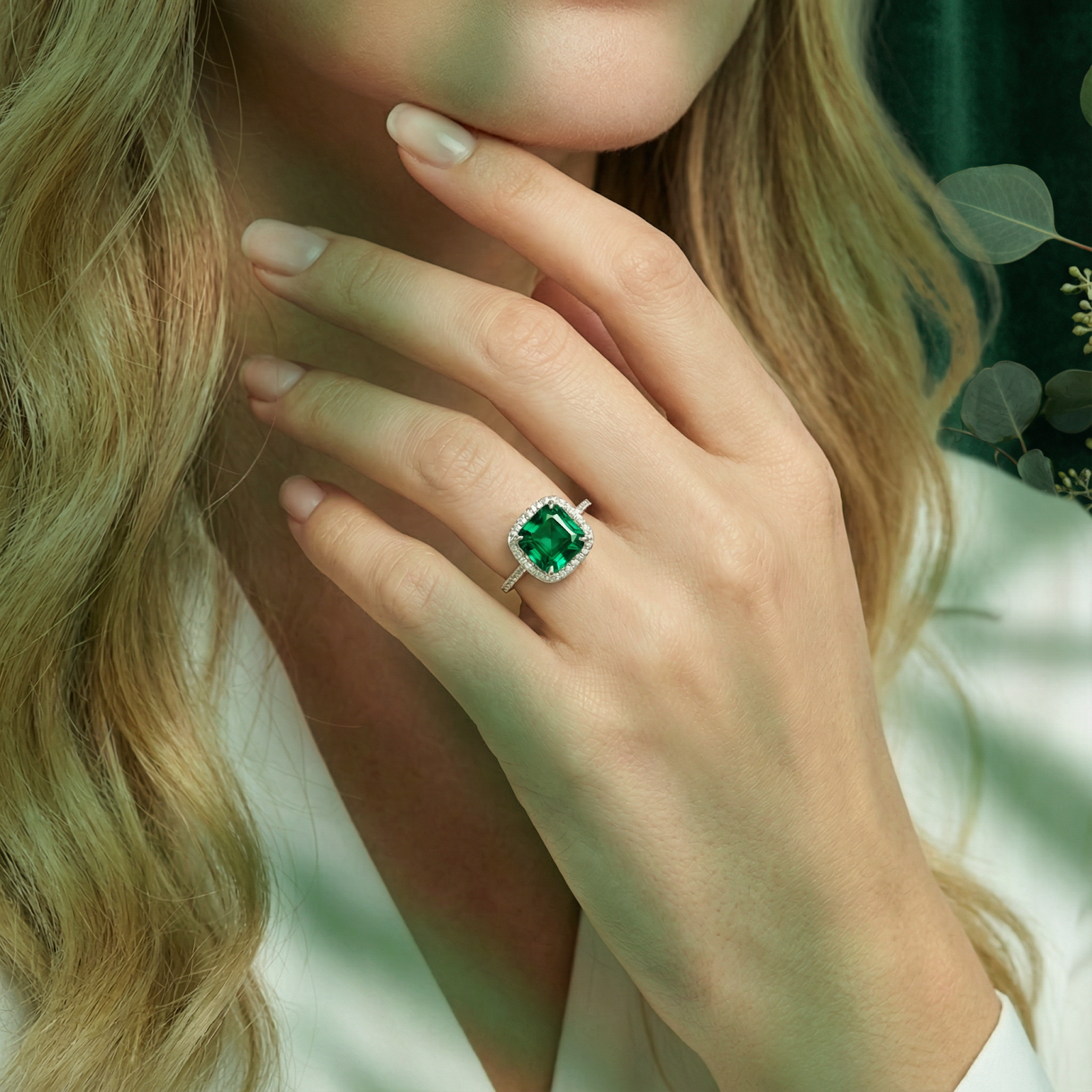 Woman wearing the cushion-cut simulated emerald sterling silver halo ring on her ring finger.