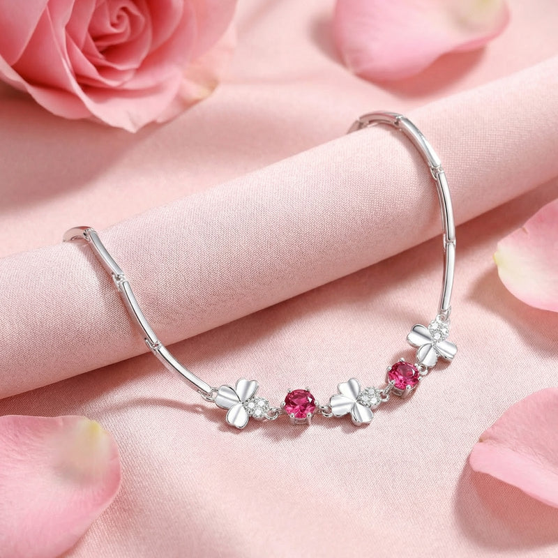 S925 sterling silver clover bracelet featuring round pink tourmaline stones draped on pink silk fabric.