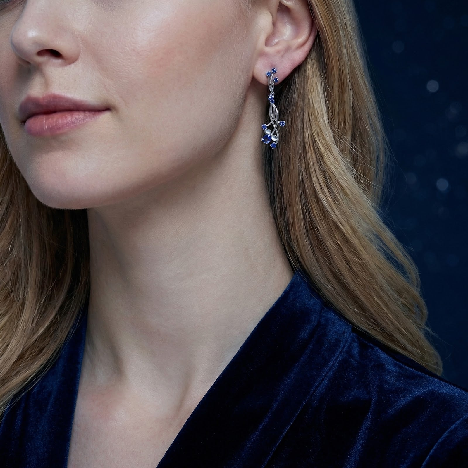 Model wearing the Nerise vine drop earring in sterling silver with blue simulated sapphires for a September birthstone.