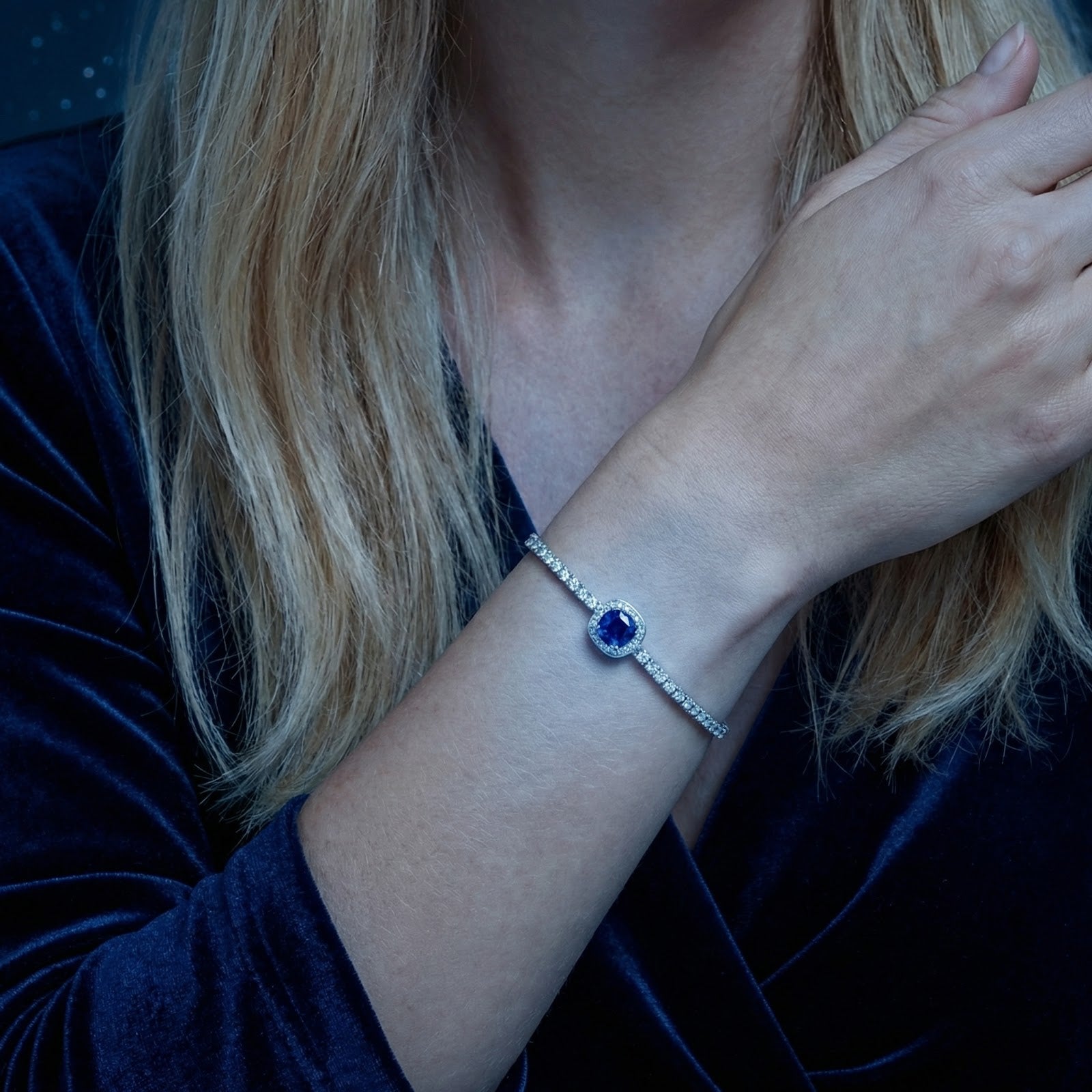 Close-up of a sterling silver adjustable bolo bracelet with a blue sapphire stone on a woman's wrist.